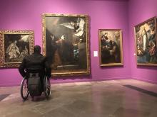 Usuario de silla de ruedas observando cuadros en el Museo