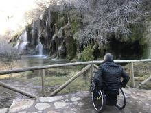 Usuario de silla de ruedas frente a la cascada del nacimiento del Río Cuervo